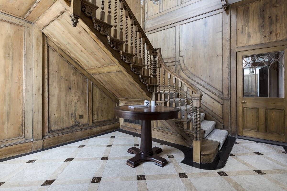 Panelled entrance hall with carved barley-twist staircase and a honed limestone floor laid in a bespoke lattice with marble cabochons