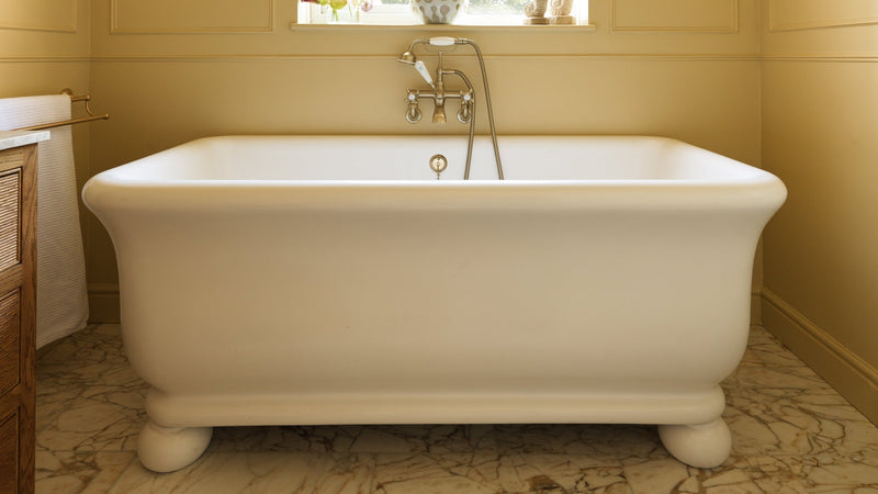 Butter yellow family bathroom with freestanding bath beneath the window and Ottoman Marble Honed flooring
