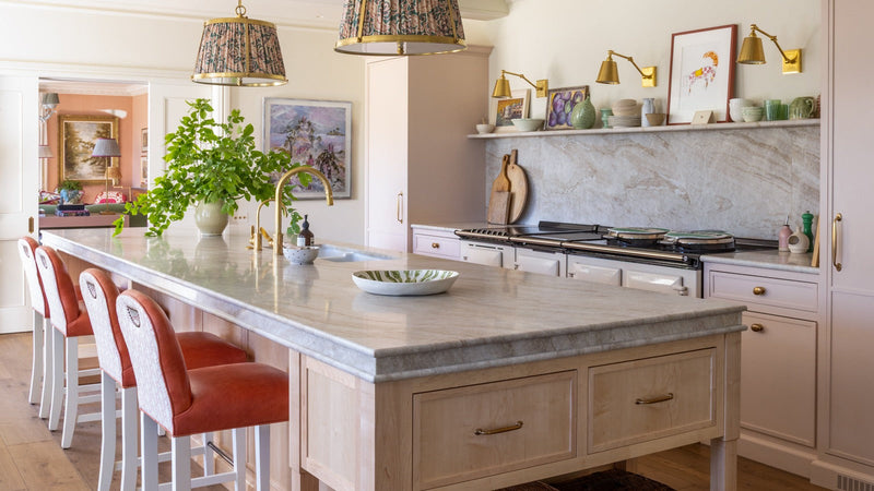Kitchen island with a Taj Mahal Quartzite worktop and orange leather bar stools