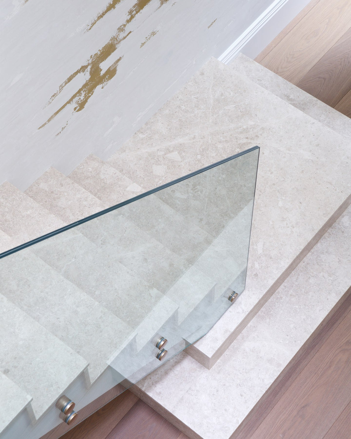 Piccadilly Limestone Honed Slab used for staircase treads and a landing, with a frameless glass balustrade and oak flooring