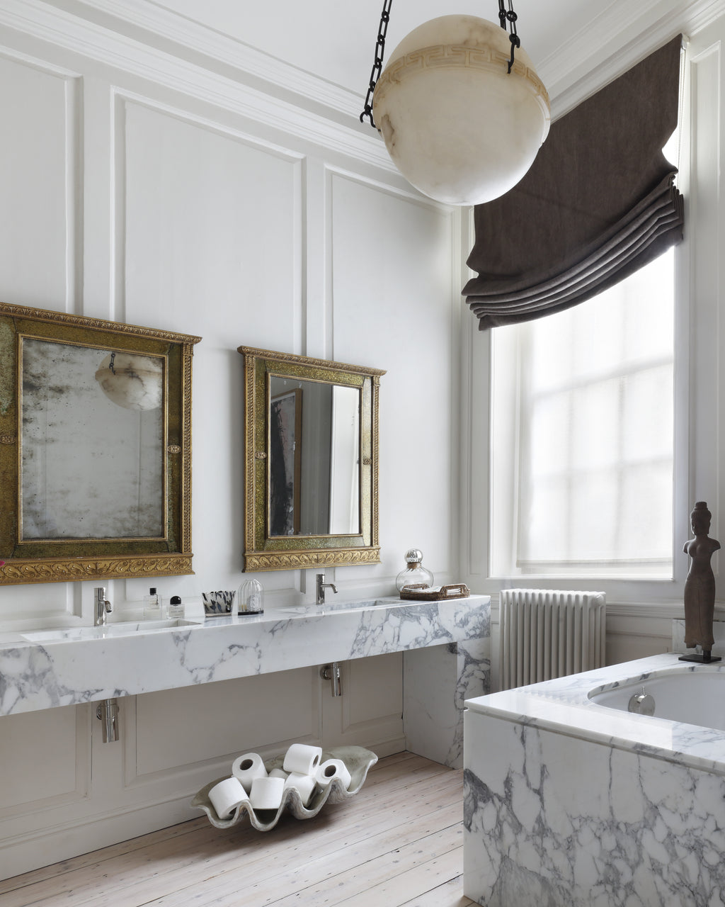 Arabescato Marble Slab forming a twin washstand and bath surround in a panelled bathroom with gilt mirrors and an alabaster pendant