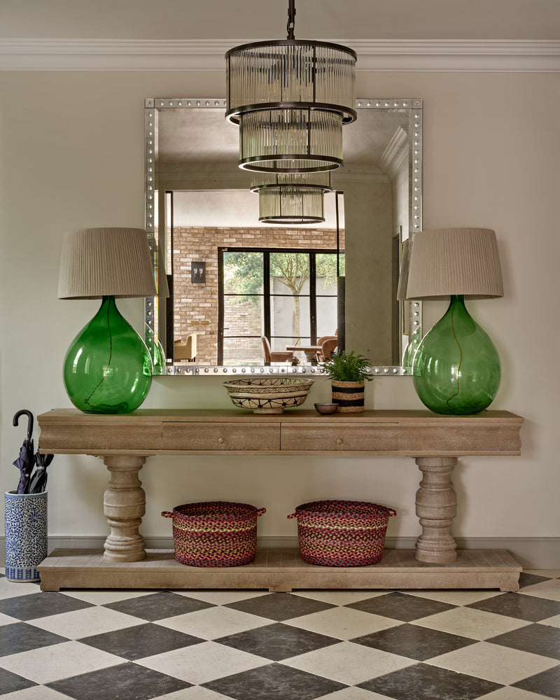 Bergamo Limestone Lightly Seasoned Finish laid as a chequerboard with Royal Mink Limestone in an entrance hall with a stone console table and green glass lamps