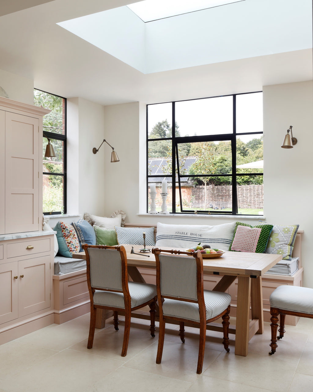 Blandford Limestone Tumbled Finish flooring in a skylit breakfast area with a built-in banquette, oak table and antique chairs
