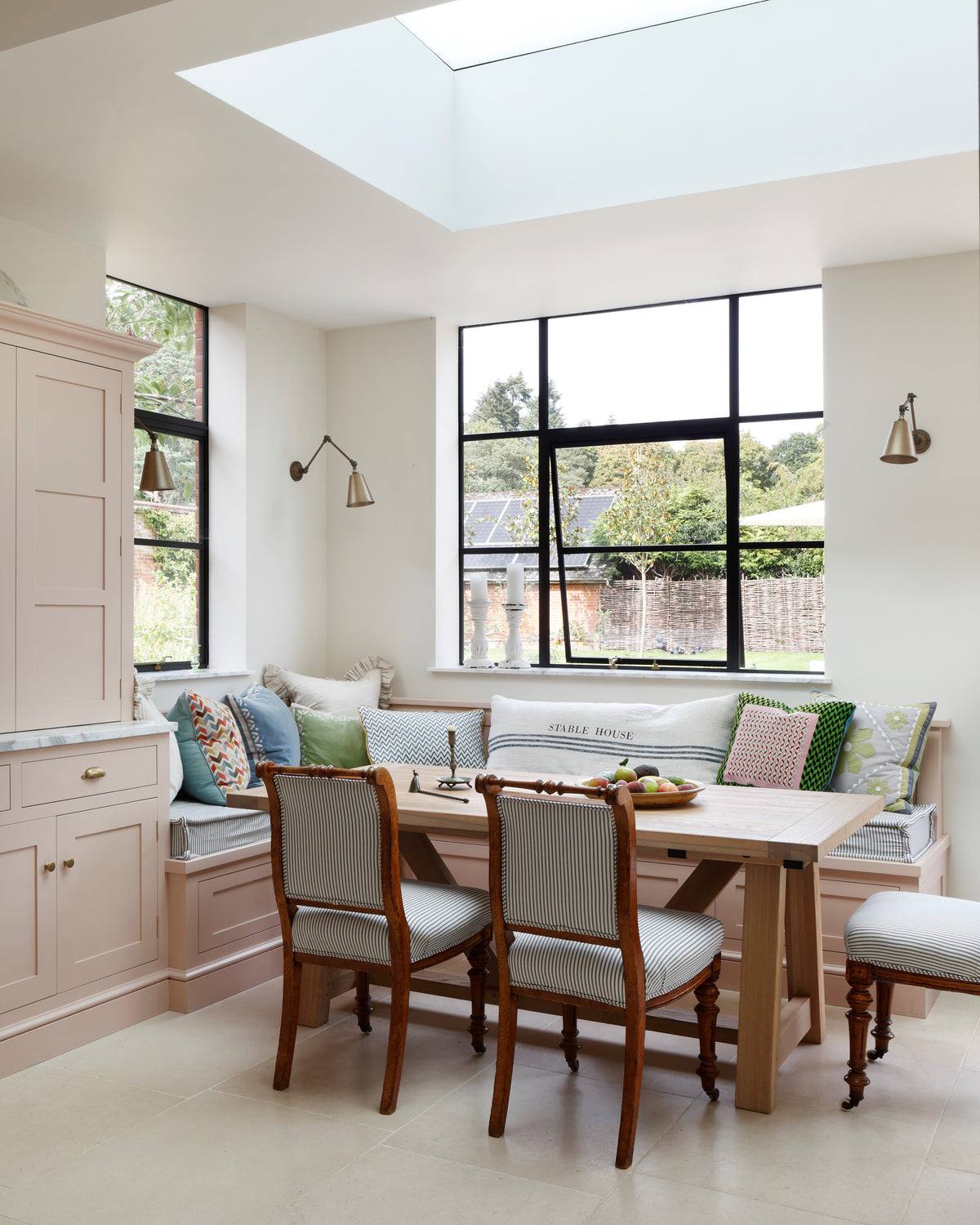 Blandford Limestone Tumbled Finish flooring in a skylit breakfast area with a built-in banquette, oak table and antique chairs