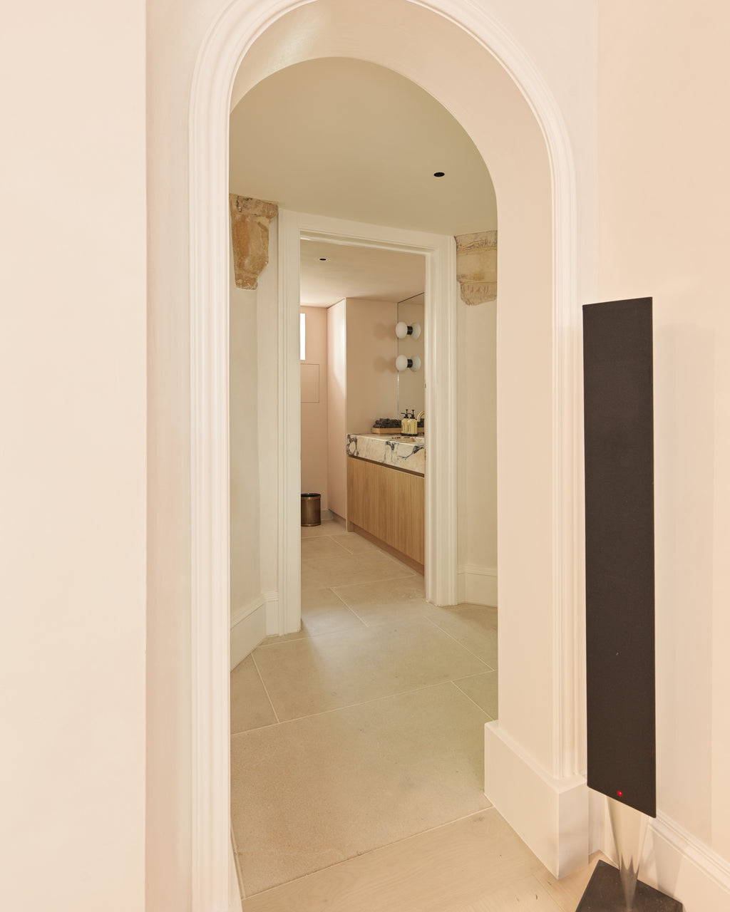 Buscot Limestone Etched Finish flooring seen through a plaster arch into a cloakroom with an oak vanity and marble basin
