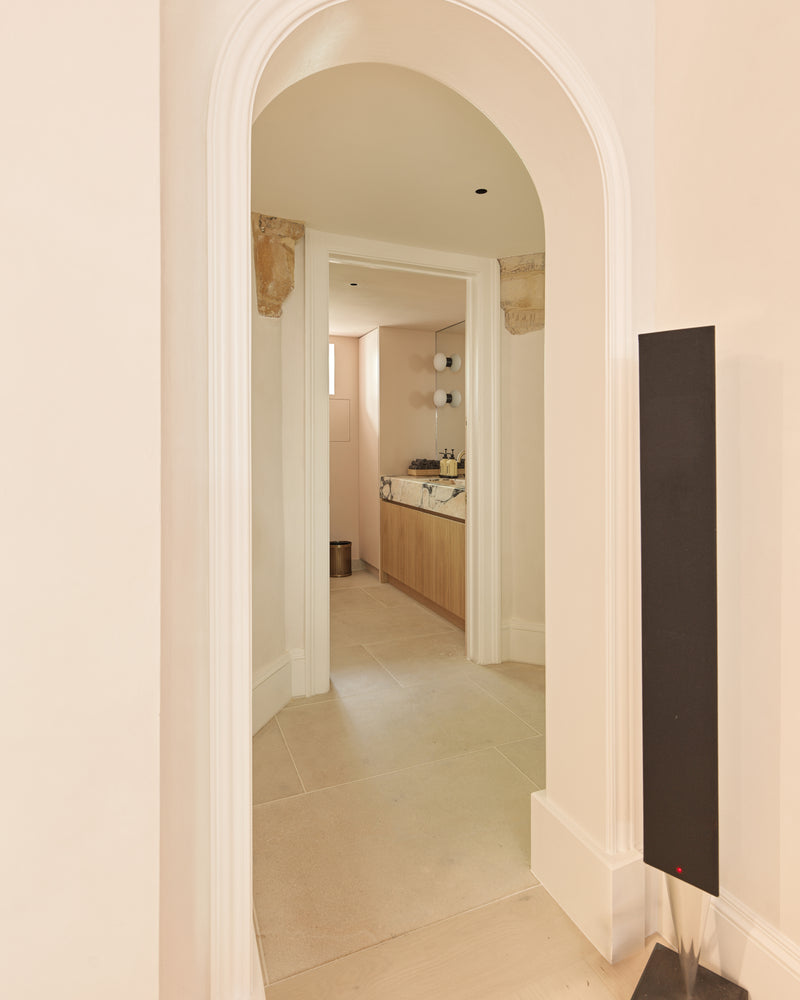 Buscot Limestone Etched Finish flooring seen through a plaster arch into a cloakroom with an oak vanity and marble basin