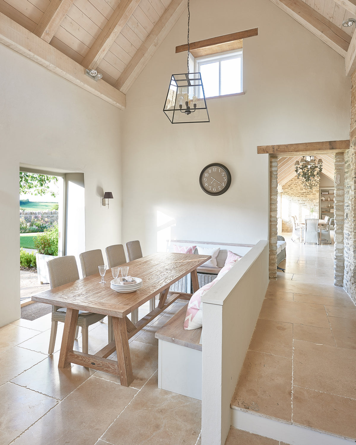 Buscot Limestone Seasoned Finish flooring in a vaulted barn dining room with a limed oak refectory table, pew bench and lantern pendant