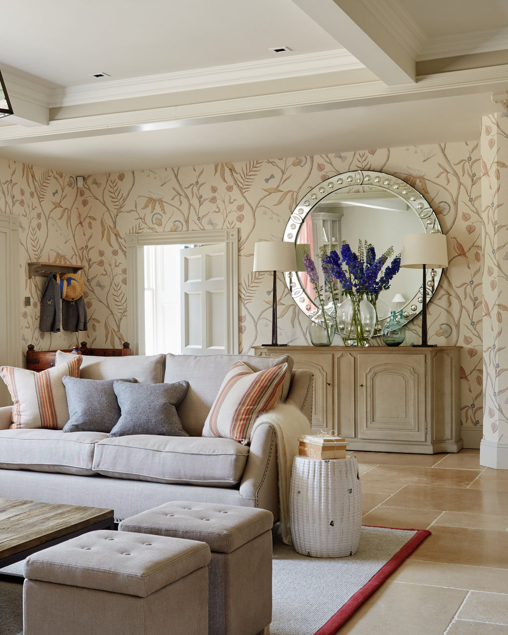 Buscot Limestone Seasoned Finish flooring in a drawing room with linen sofas, a round Venetian mirror and hand painted botanical wallpaper
