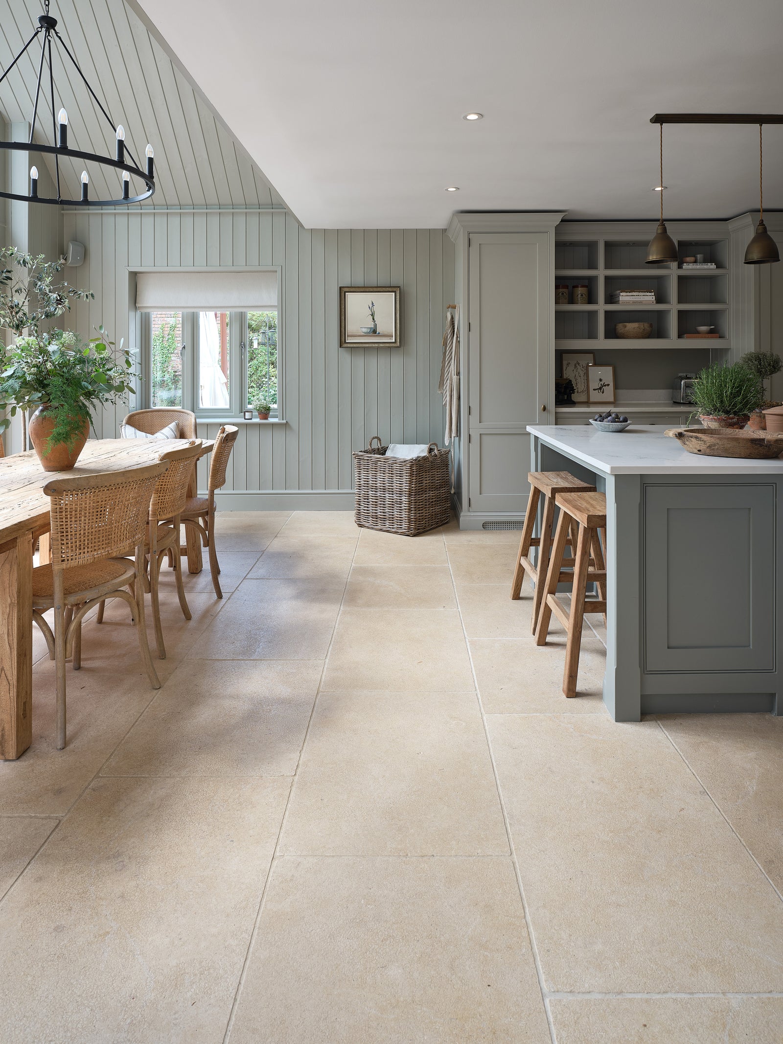 Buscot Limestone Tumbled & Etched flooring running through a panelled kitchen and dining space with a rustic oak table