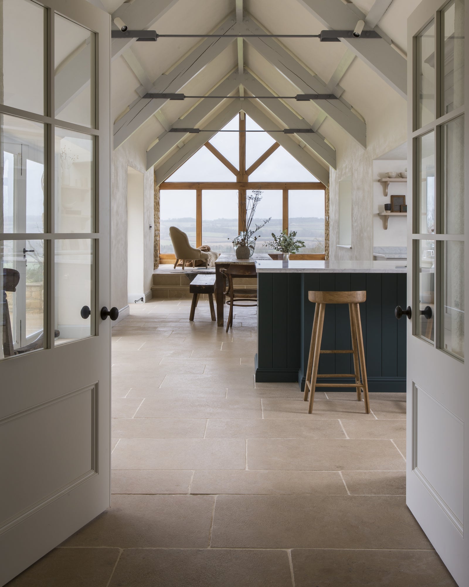 Buscot Limestone Tumbled Finish flagstones running through a vaulted barn kitchen towards a glazed gable with open countryside beyond