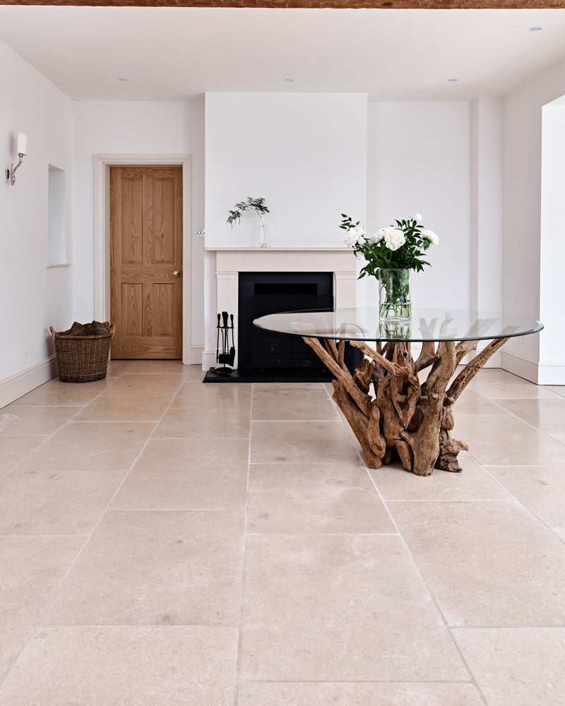 Buscot Limestone Tumbled Finish laid across a pale open-plan living room with a stone fireplace and a driftwood and glass dining table