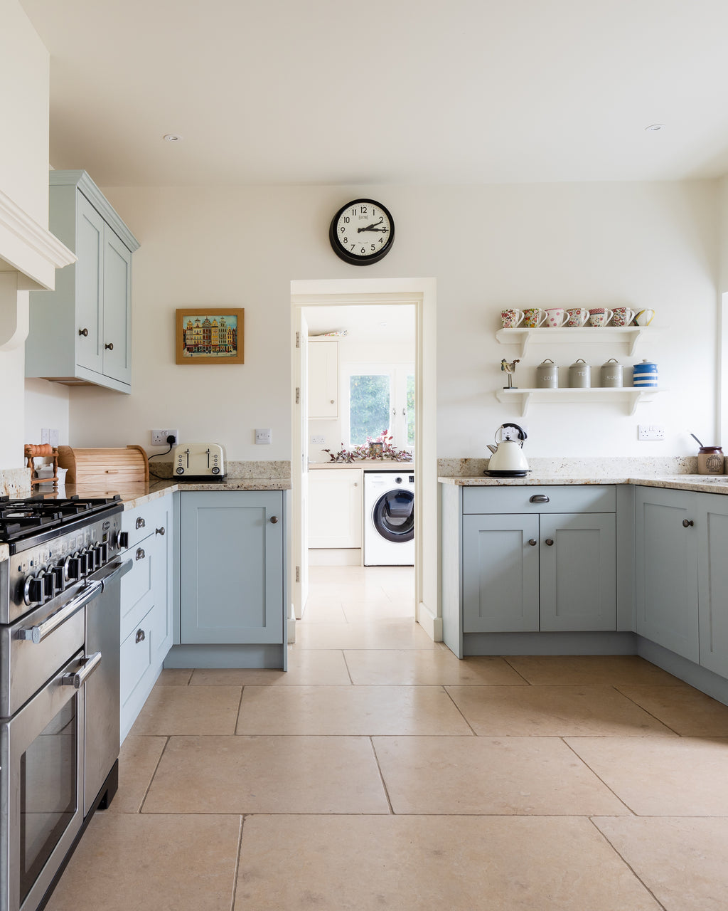 Buscot Limestone Tumbled Finish flooring through a pale blue shaker kitchen and on into the utility room beyond