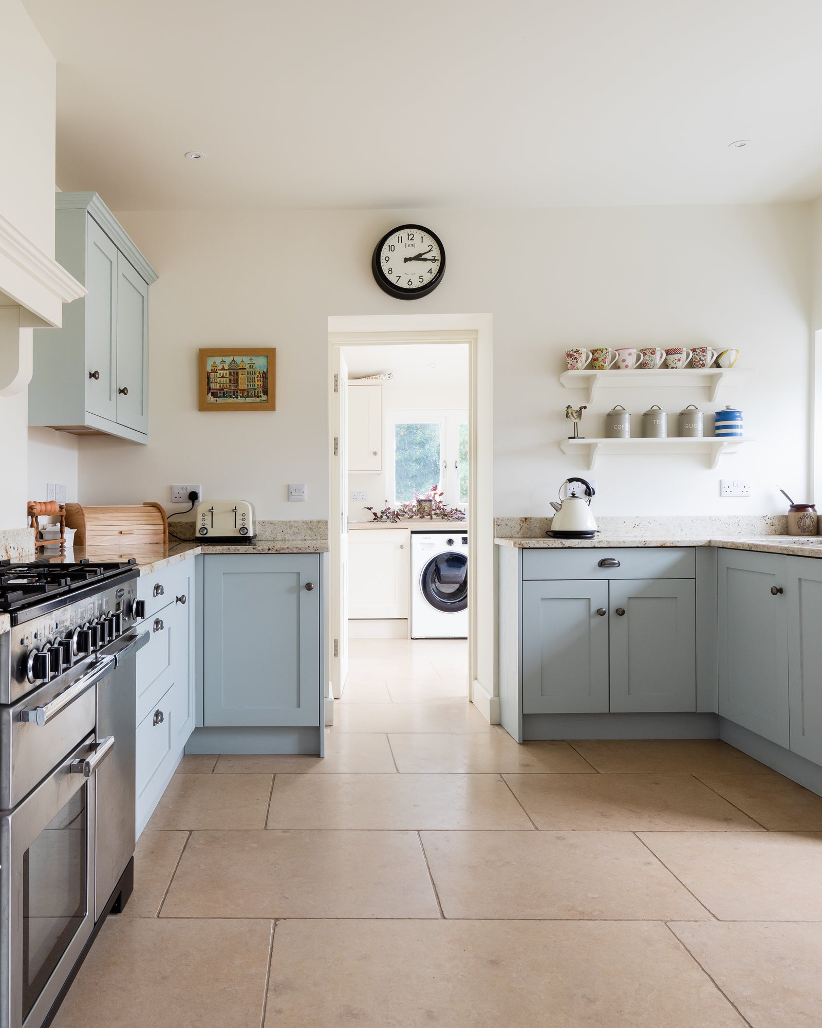 Buscot Limestone Tumbled Finish flooring through a pale blue shaker kitchen and on into the utility room beyond