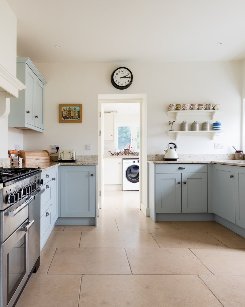 Buscot Limestone Tumbled Finish flooring through a pale blue shaker kitchen and on into the utility room beyond
