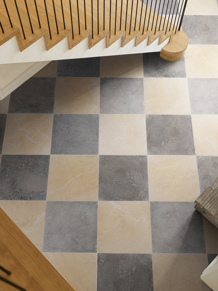 Overhead view of a grey and cream chequerboard stone floor beside an oak and steel staircase