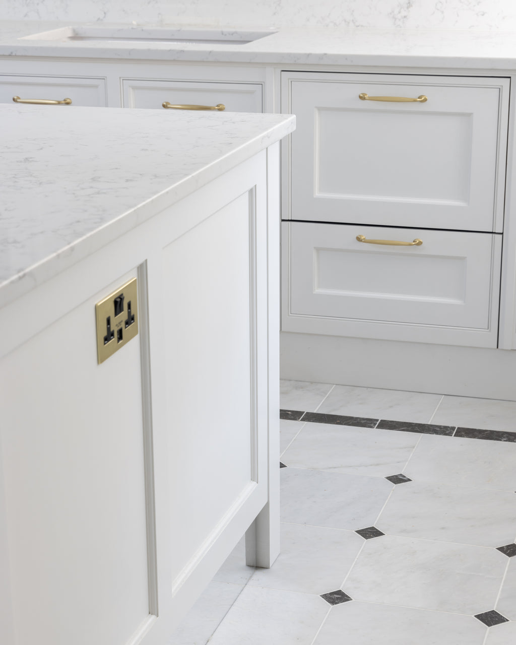 Carrara C Marble Slab as a kitchen island worktop with a bullnose edge, above a pale marble floor laid with dark cabochon insets