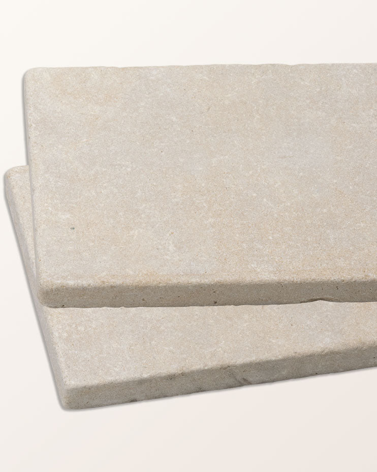Two Castilan Limestone Cobbles Tumbled tiles stacked at an angle against a plain background, showing the tumbled edge and the pale honeyed surface