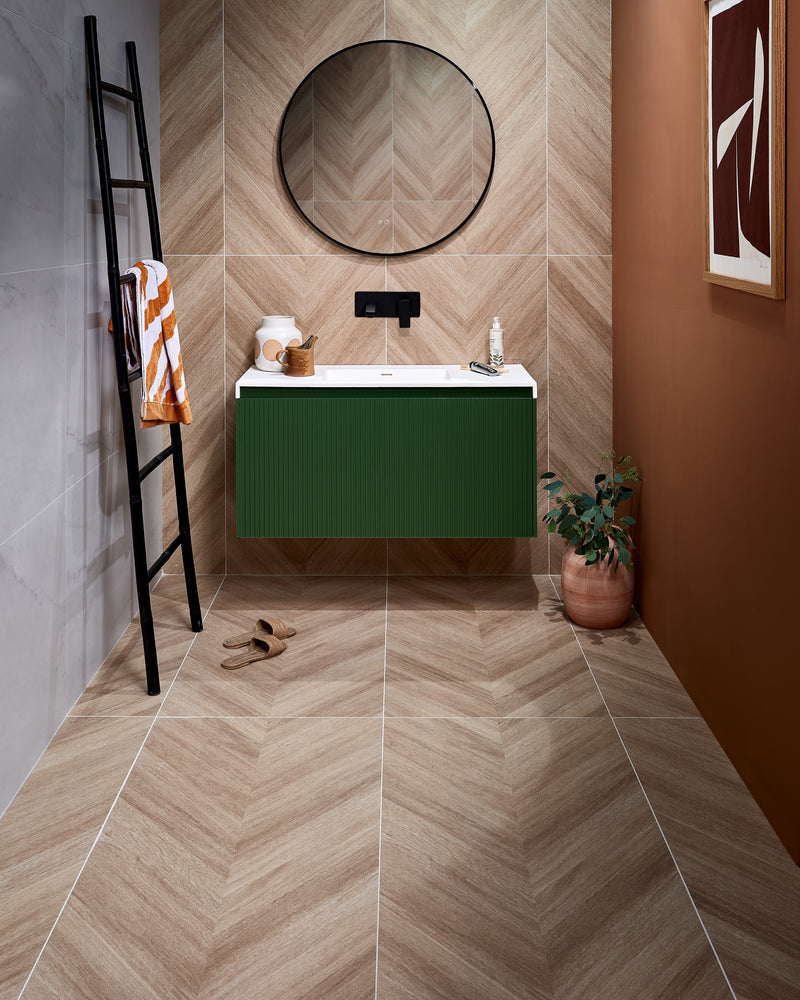 Davos Chevron Porcelain Matt laid in a chevron across the floor and up the wall of a cloakroom, with Mystery White Porcelain Matt on the side wall, a green fluted vanity and a black leaning towel ladder