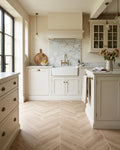Davos Chevron Porcelain Matt laid across the floor of a cream shaker kitchen with a marble splashback, a butler sink with brass taps and black steel windows