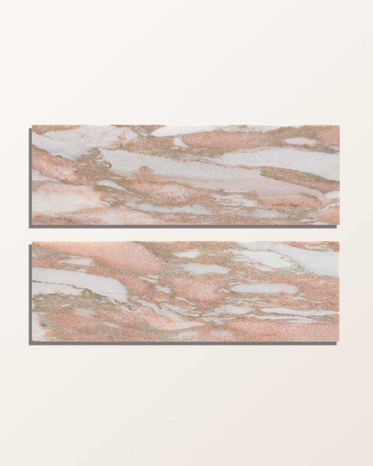 Two bricks of East Java Flamingo Marble Honed Brick laid flat and face-on against a plain cream background, the pink, white and grey-gold veining running lengthways