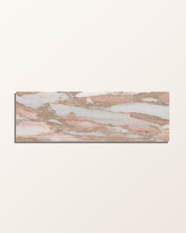 A single brick of East Java Flamingo Marble Honed Brick face-on against a plain cream background, showing the soft pink and white marbling
