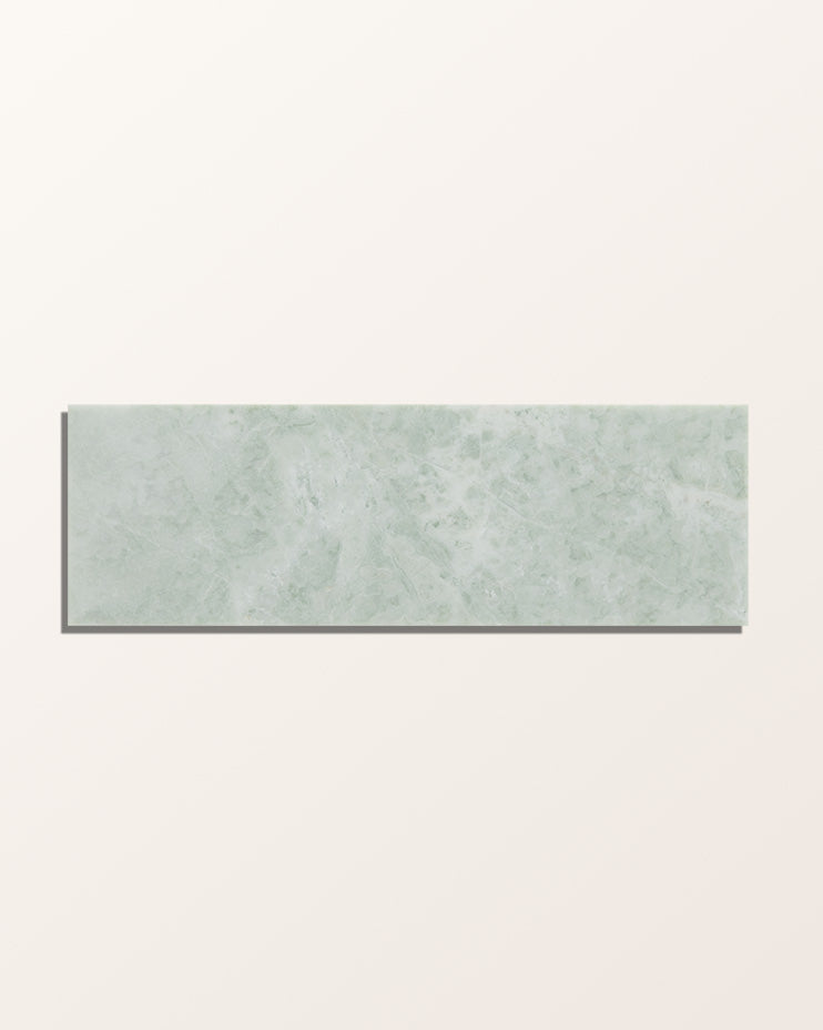 A single brick of East Java Hummingbird Marble Honed Brick face-on against a plain cream background, showing the soft green marbling and pale gold veining