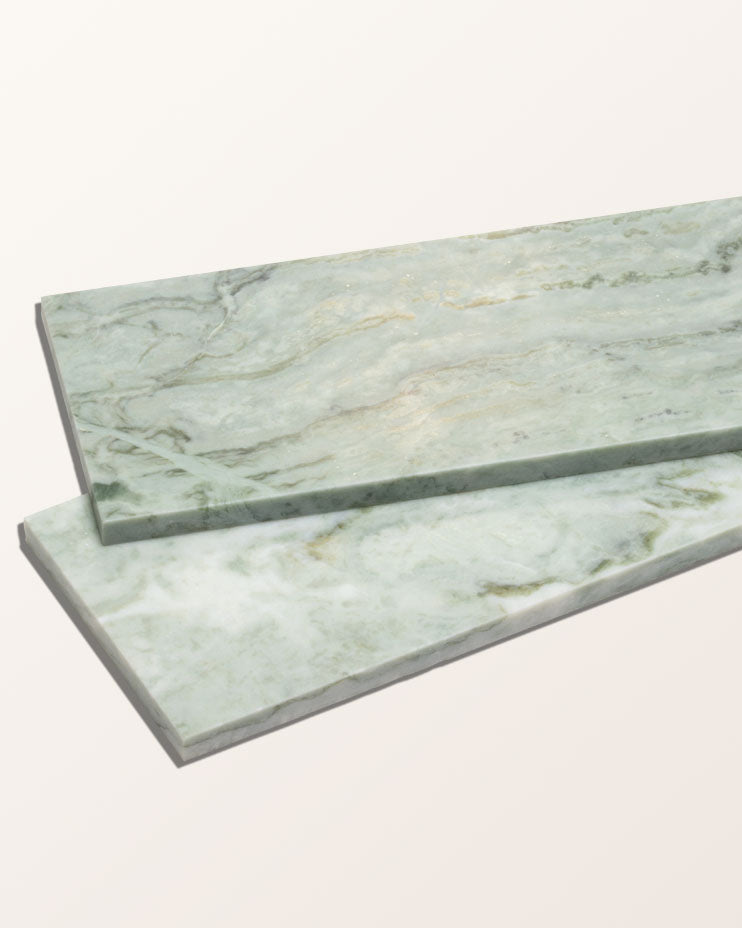 East Java Hummingbird Marble Honed Brick shown as two bricks resting at an angle against a plain cream background, showing the honed face and the pale green and gold veining