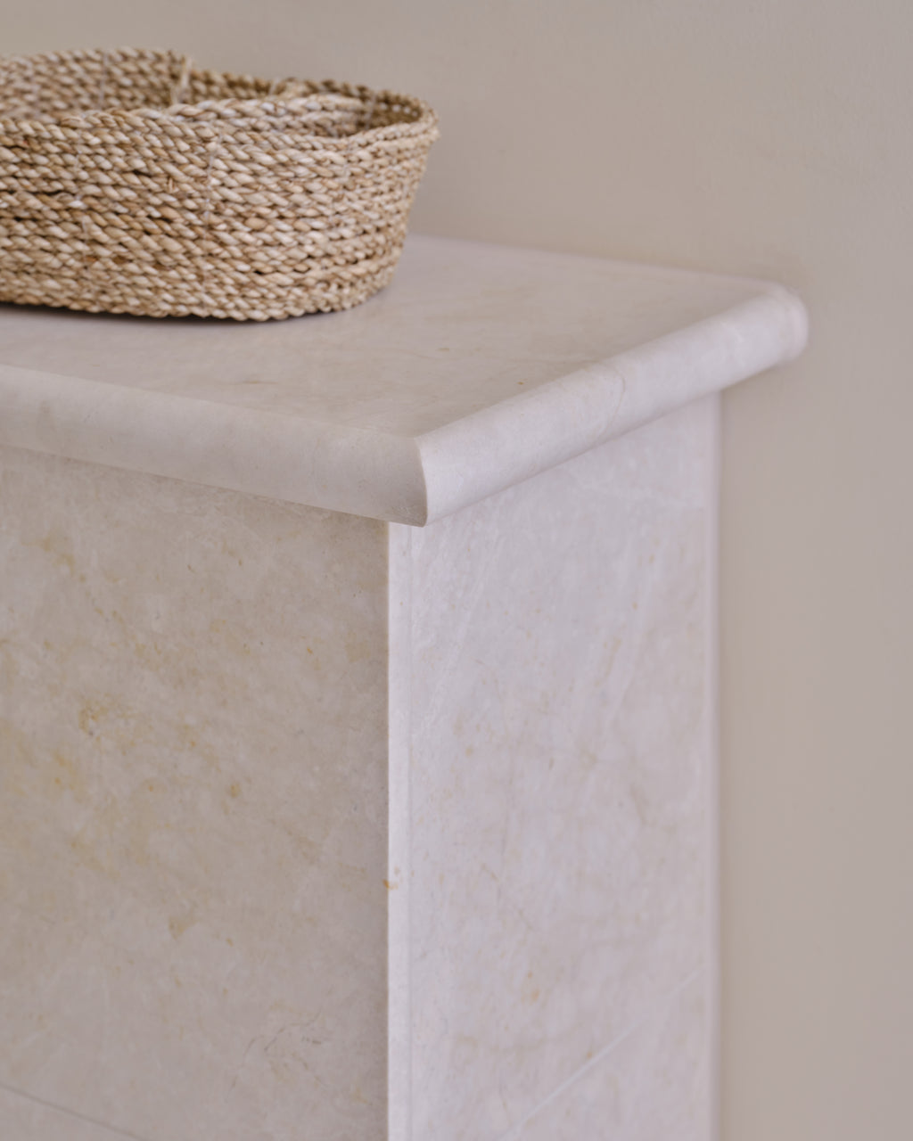 Folio Marble Honed Finish bullnose capping detail on a stone-clad wall top with a woven basket resting on it