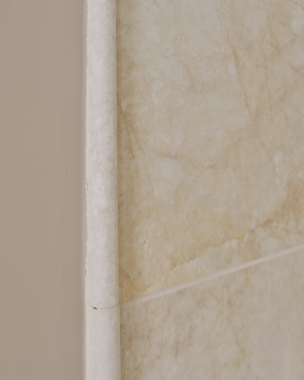 Folio Marble Honed Finish close-up of a pencil-round edge trim meeting the painted wall, showing the honed surface and soft ochre veining