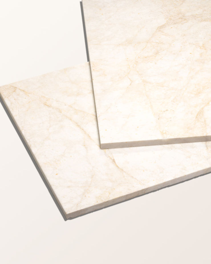 Folio Marble Honed Finish packshot of two tiles stacked at an angle, showing the honed face and soft ochre veining