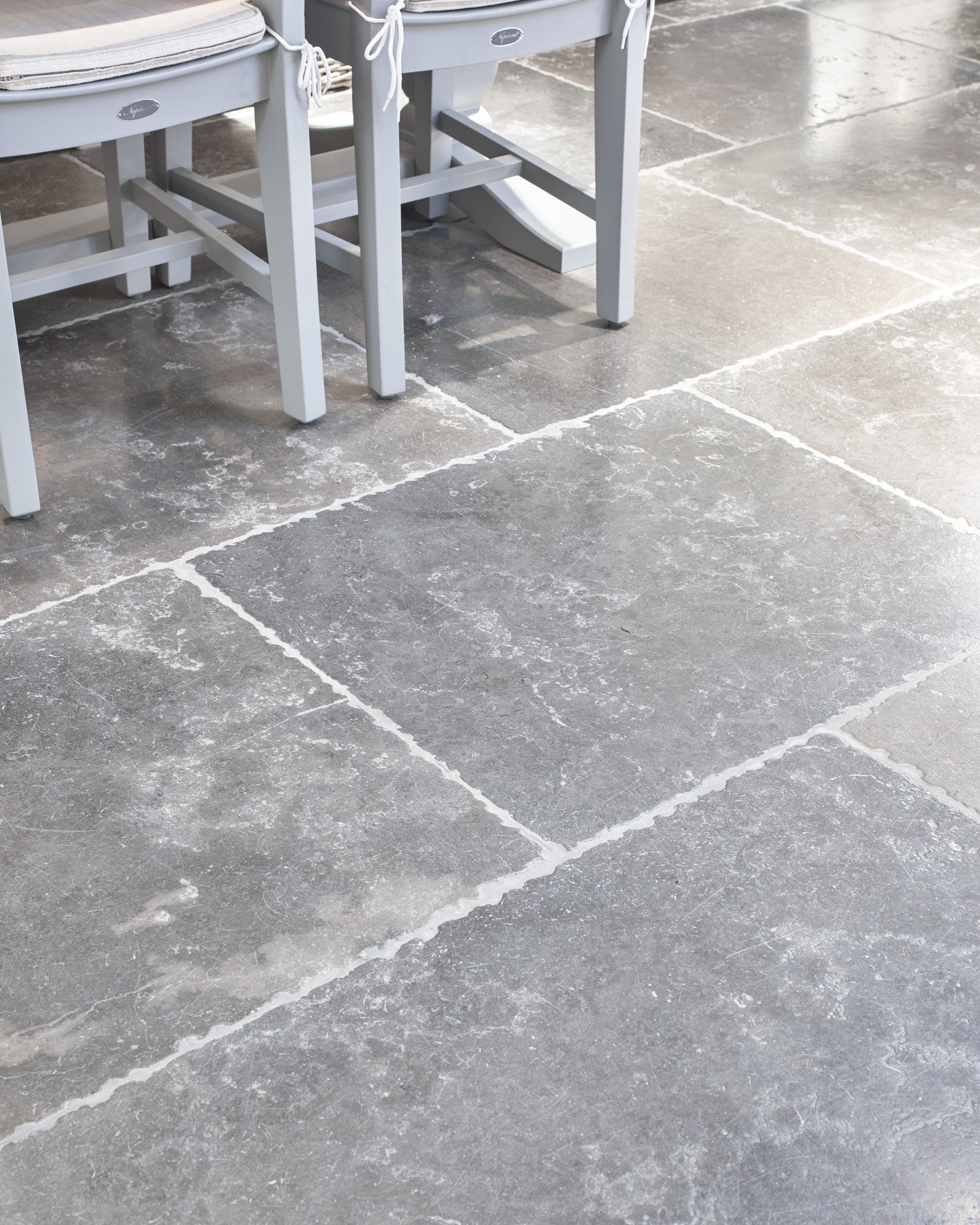 Close view of Hazlebury Limestone Seasoned Finish showing the tumbled edges, pale grout lines and mottled grey surface
