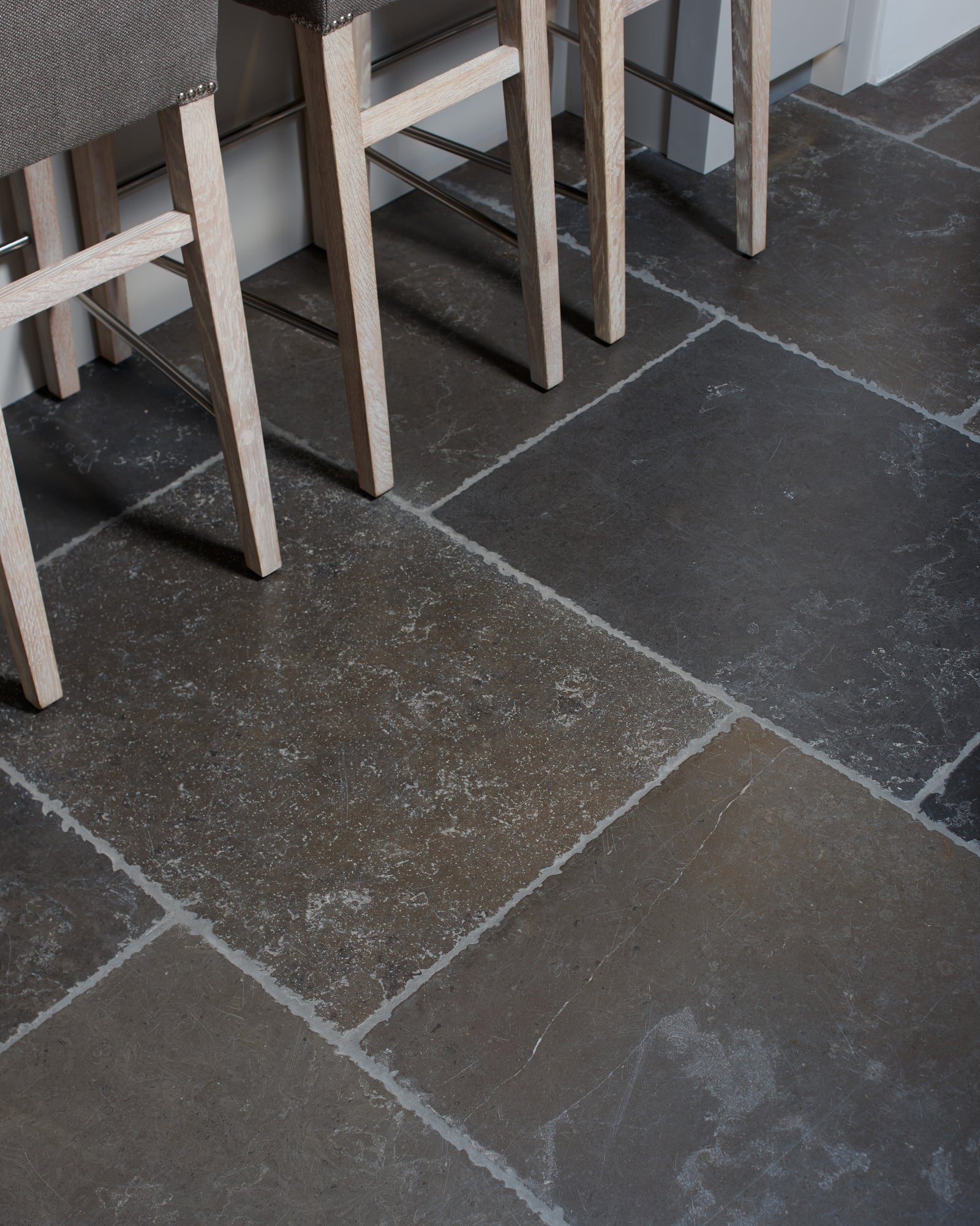 Hazlebury Limestone Seasoned Finish laid in large format beneath limed oak bar stools at a kitchen island
