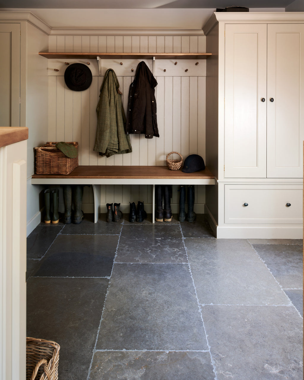 Hazlebury Limestone Seasoned Finish in a boot room, with riding boots under an oak bench and coats on a painted peg rail