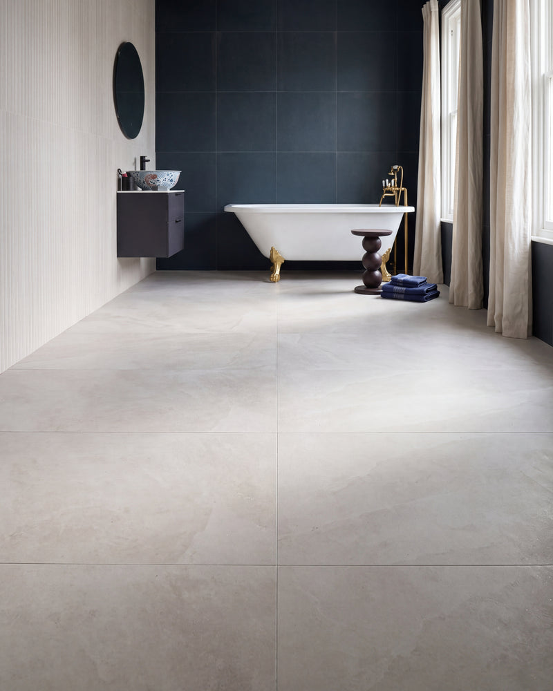 Himalaya Porcelain Crystal Textured in large format across a bathroom floor, with a gold-footed roll-top bath against a deep blue tiled wall and a fluted white wall behind the vanity