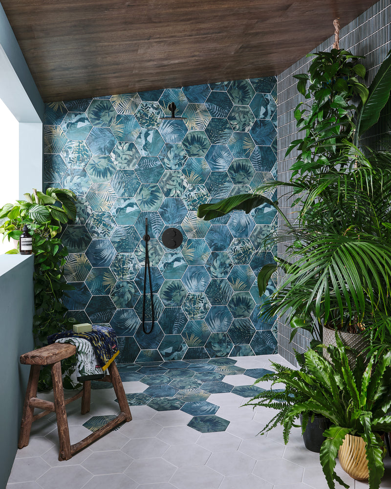 Jungle Porcelain by Clarissa Hulse covering a walk-in shower wall and spilling onto the floor, under a timber ceiling and surrounded by trailing houseplants