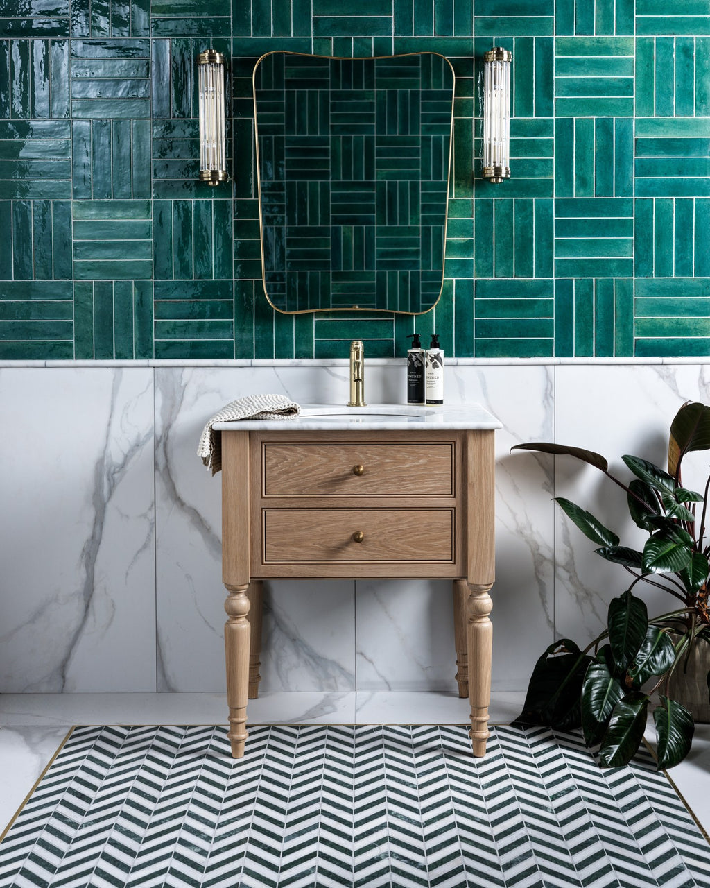 Kensington Porcelain Matt used as a marble effect half wall below green glazed tiles in a cloakroom, with an oak vanity and chevron mosaic floor