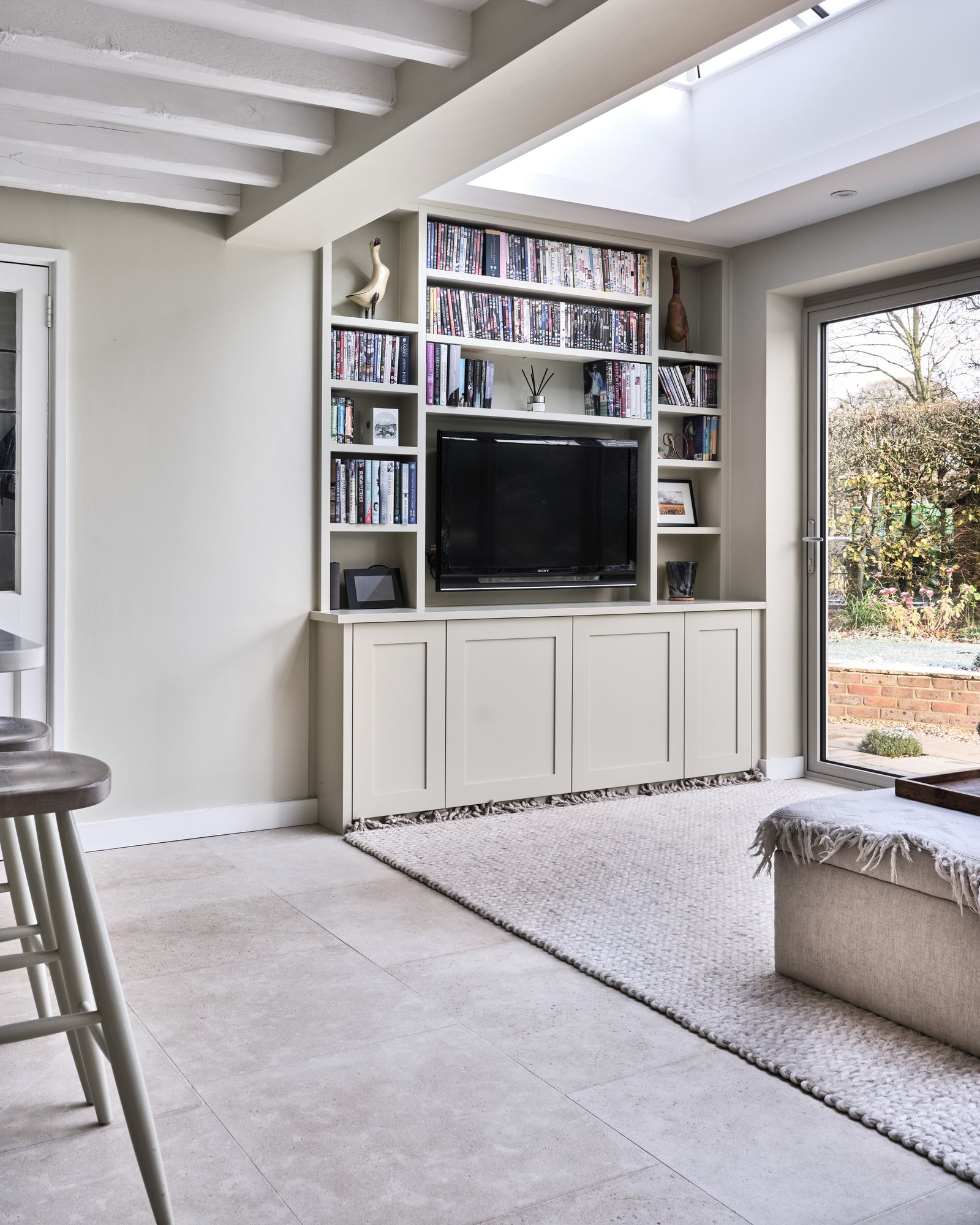Kimmeridge Limestone Etched Finish across a snug beneath a skylight, with built-in bookshelves, a woven rug and garden doors open onto a brick terrace