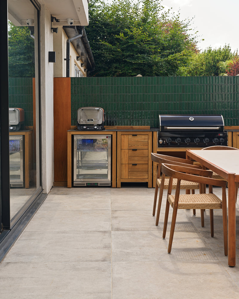 Kimmeridge Limestone Paving Etched Finish underfoot in an outdoor kitchen, with a teak grill run set against a Petite Green Gloss tiled wall