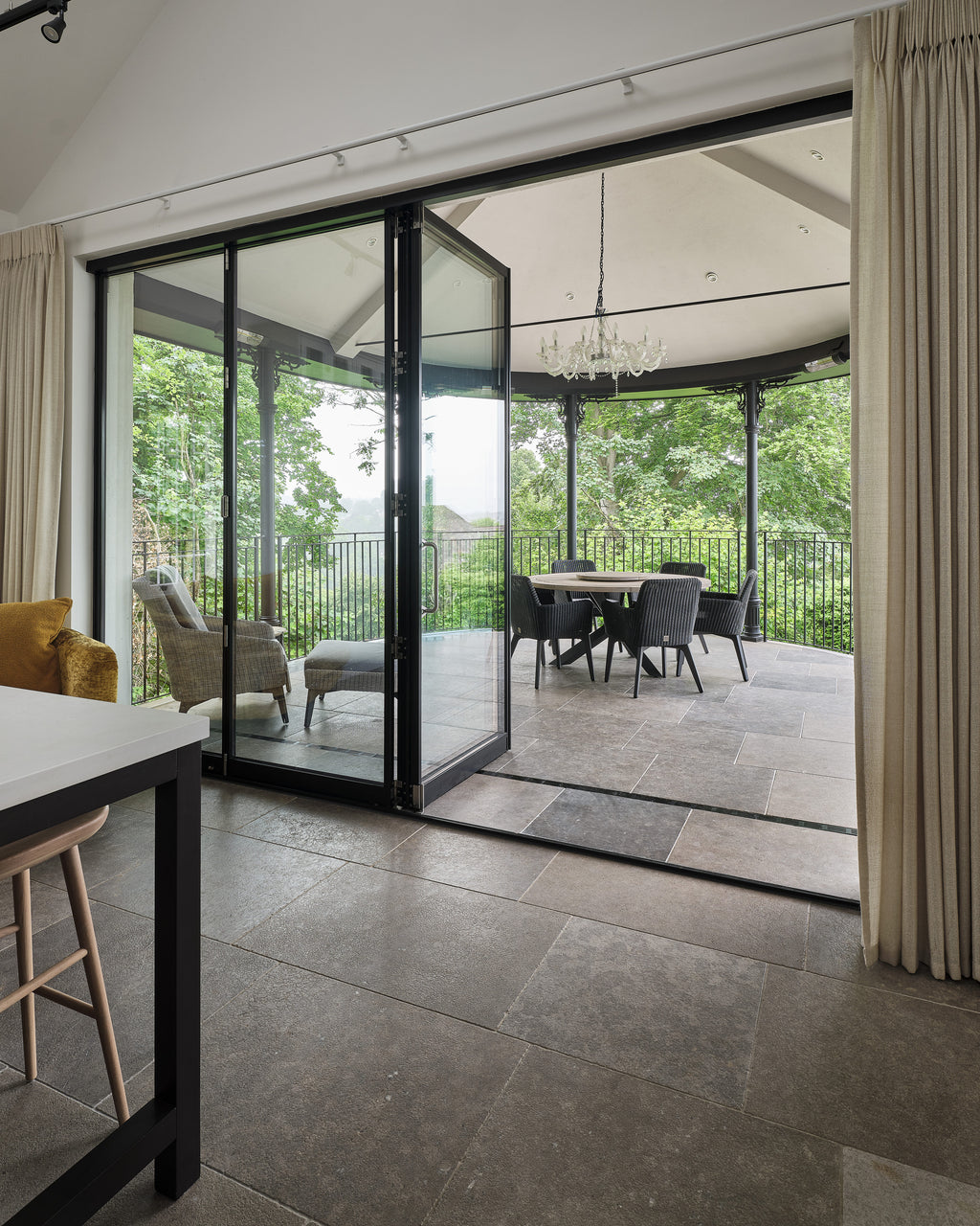 Kimmeridge Limestone Tumbled & Etched Finish running from a kitchen floor straight out through open sliding doors onto the veranda beyond