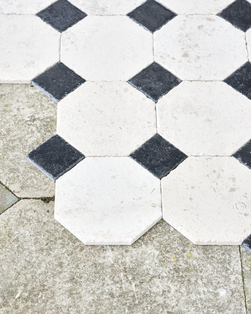 Limoges Limestone Vintaged Finish octagons and Tora Blue Vintaged Cabochons meeting the edge of an old weathered flagstone path