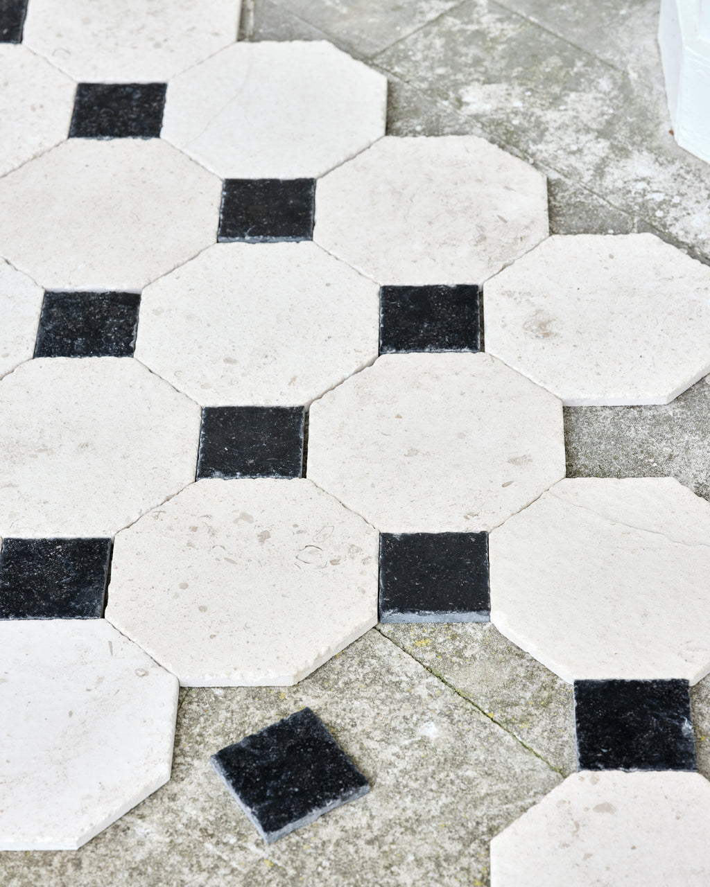 Limoges Limestone Vintaged Finish octagons set with Tora Blue Vintaged Cabochons, laid loose over outdoor flagstones to show the pattern