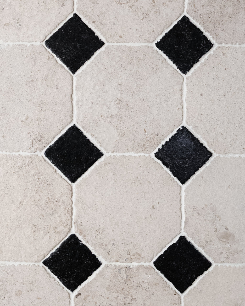 Close detail of a grouted Limoges Limestone Vintaged Finish octagon floor with Tora Blue Limestone Vintaged Cabochons