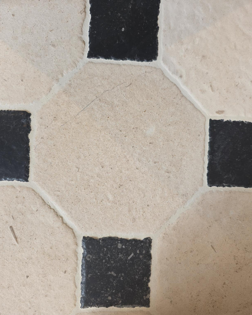 Close macro of a Limoges Limestone Vintaged Finish octagon framed by four Tora Blue Vintaged Cabochons, showing the tumbled edges and grout joints