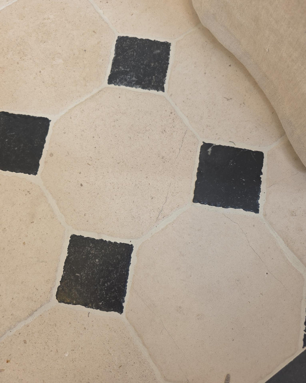 Limoges Limestone Vintaged Finish octagons and Tora Blue cabochons underfoot beside a linen floor cushion