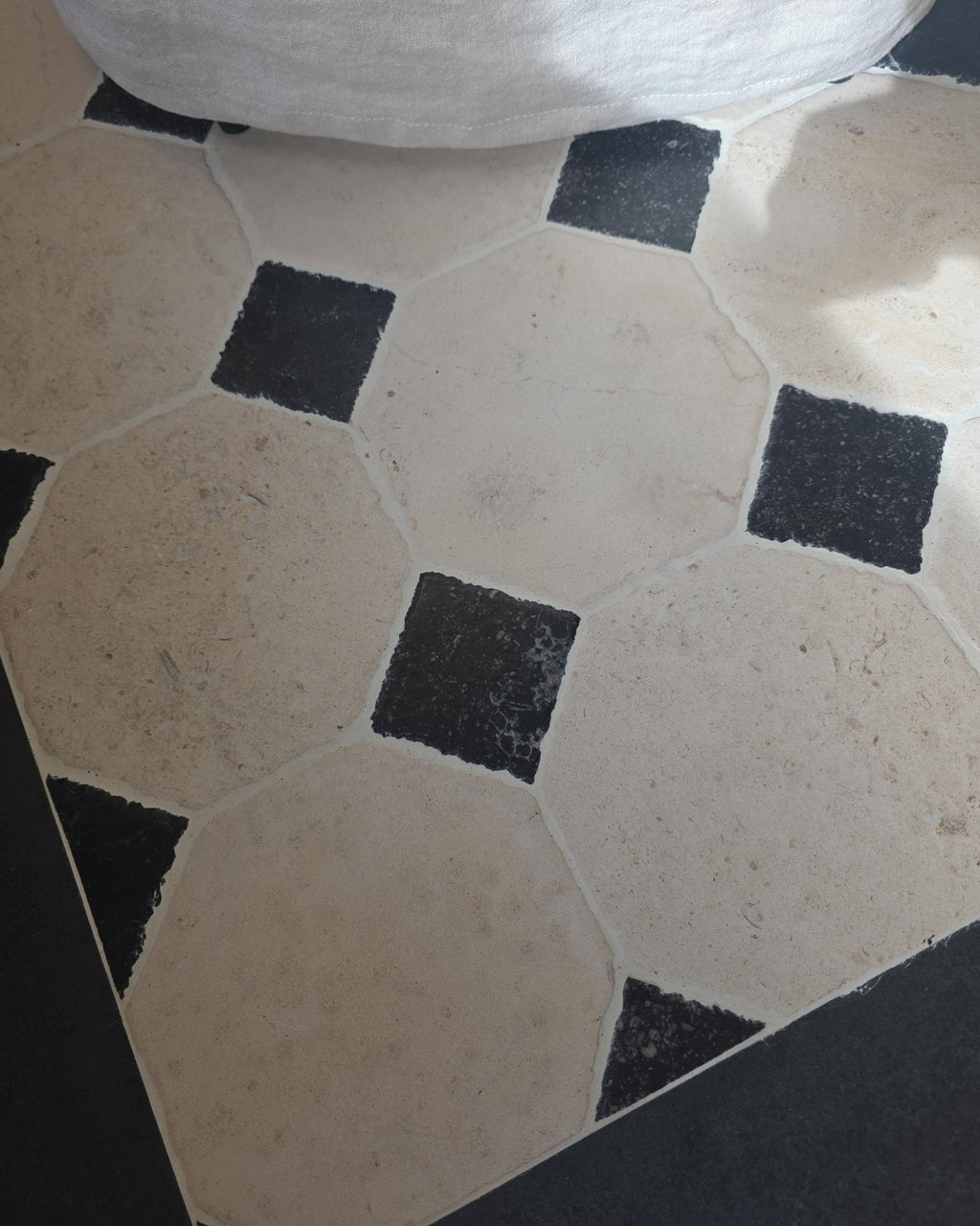 Limoges Limestone Vintaged Finish octagon floor with Tora Blue cabochons meeting a dark stone perimeter border