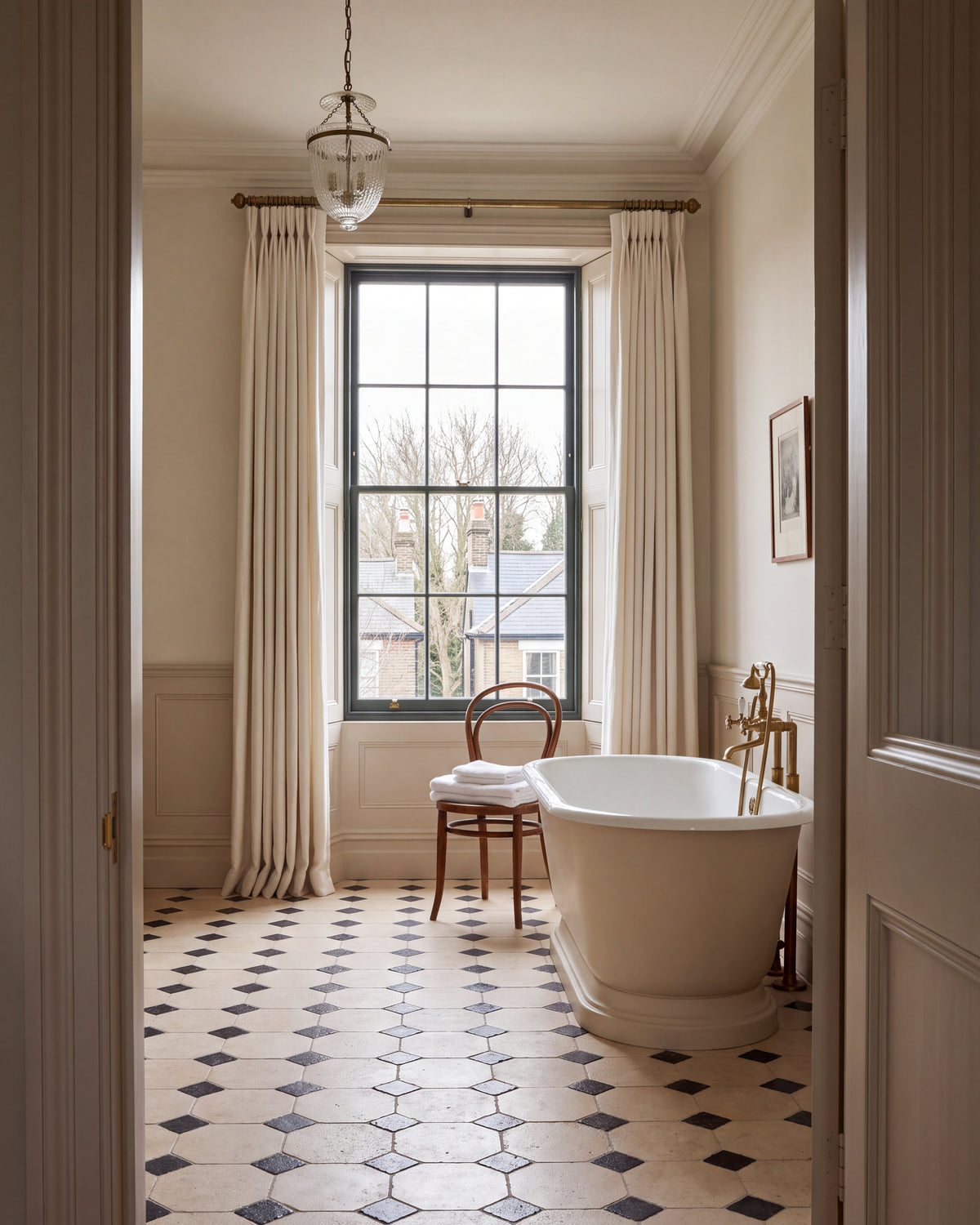 Limoges Limestone Vintaged Finish octagons with Tora Blue Limestone Vintaged Cabochons in a period bathroom with a roll-top bath, brass taps, a bentwood chair and a tall sash window