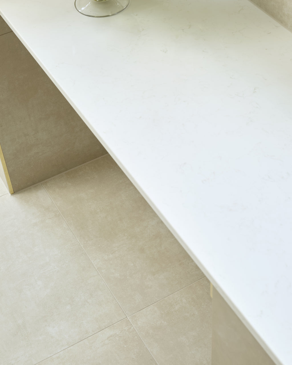 Loft Porcelain Pearl flooring beneath a slim white stone console with a glass bowl of green hydrangeas