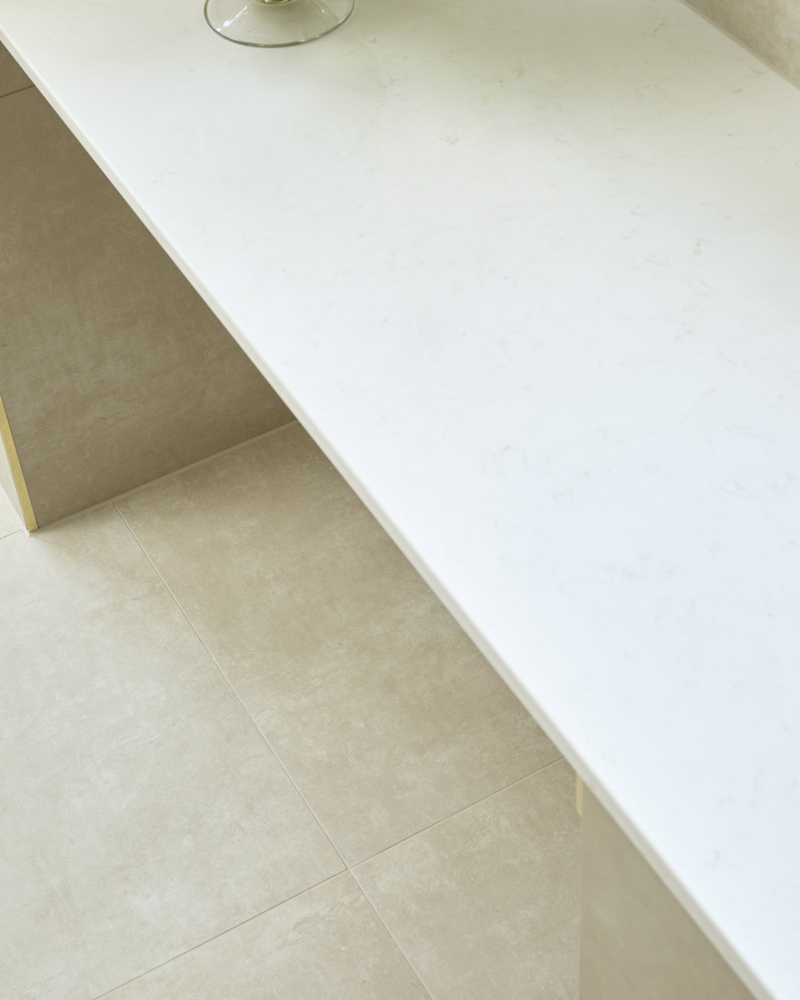 Loft Porcelain Pearl flooring beneath a slim white stone console with a glass bowl of green hydrangeas