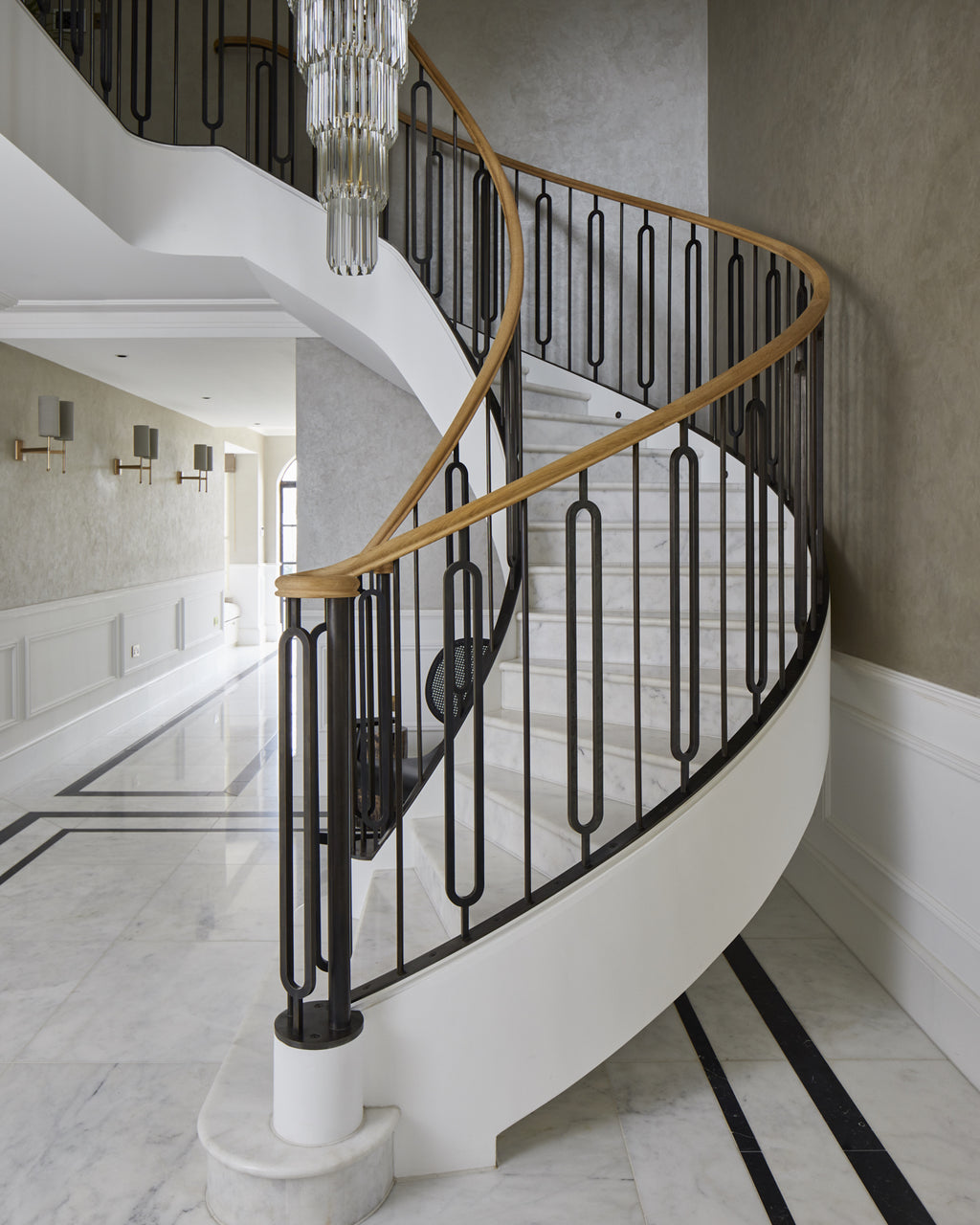 Long Island Marble Honed Finish on the treads and floor of a curved staircase with a bronze balustrade and oak handrail