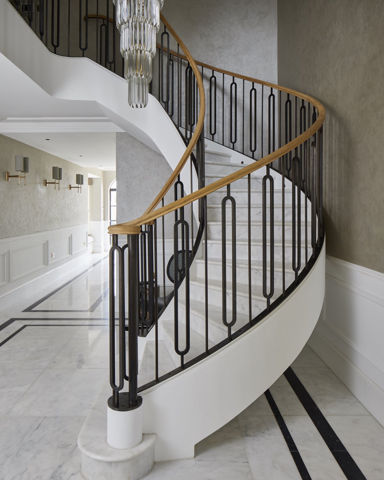 Long Island Marble Honed Finish on the treads and floor of a curved staircase with a bronze balustrade and oak handrail